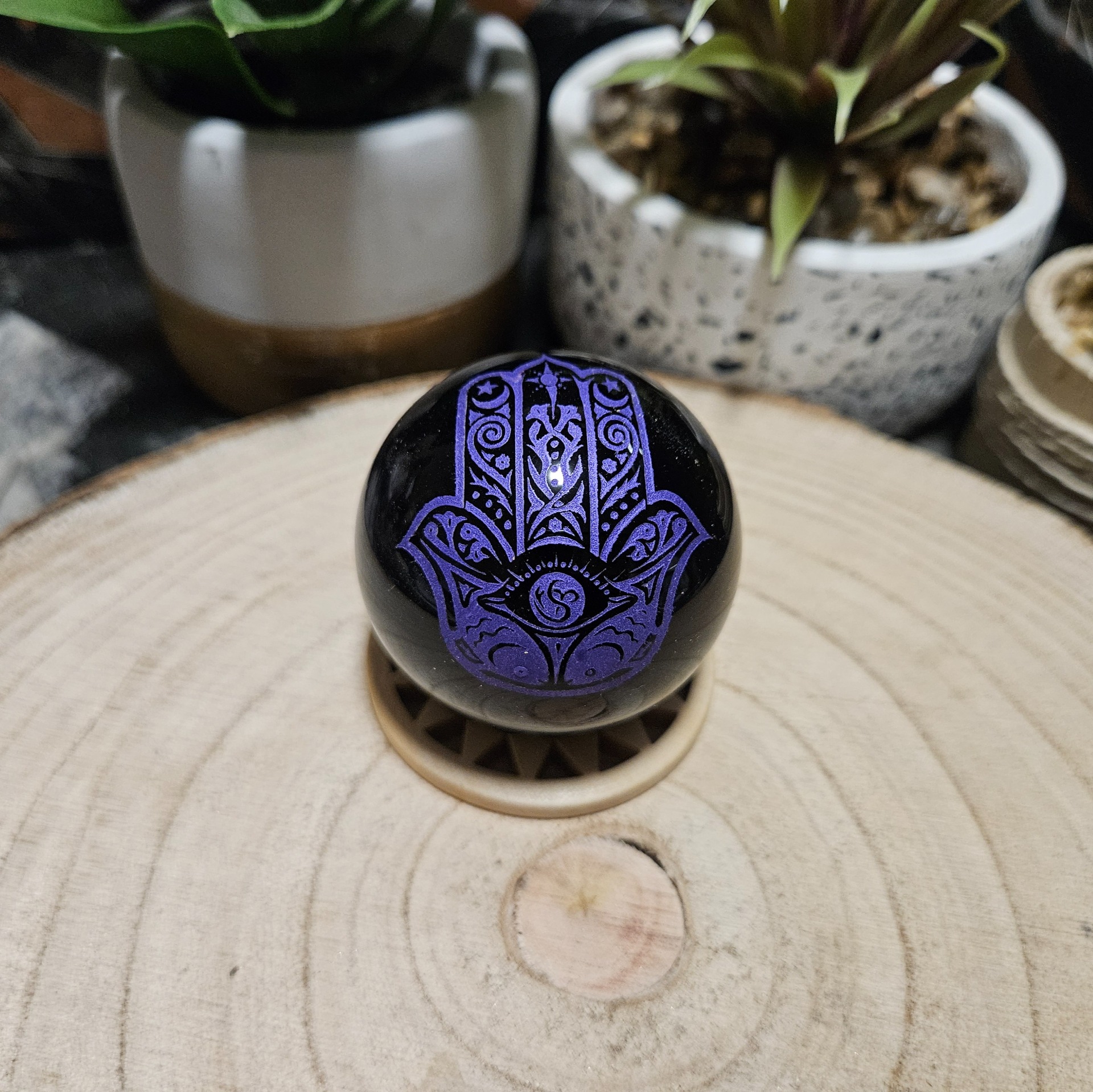 Imperial Fialová Hamsa Obsidián – Sféra božskej ochrany (Prírodná čierna obsidiánová guľa s gravírovaným fialovým symbolom Hamsa – priemer 5 cm)